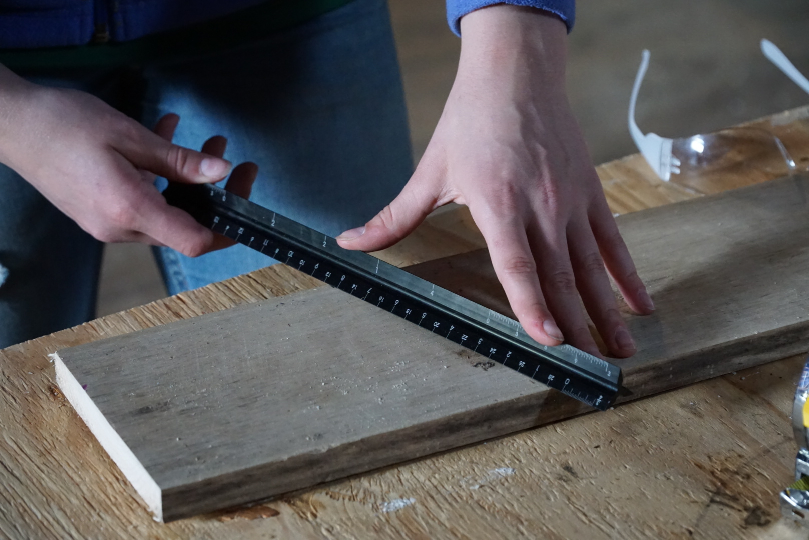 An image of a person using a ruler to make a measurement on a piece of wood.
