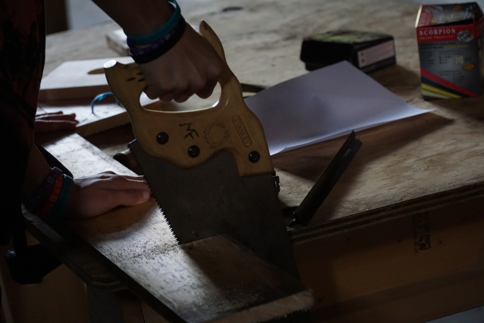 An image of someone sawing a piece of wood.